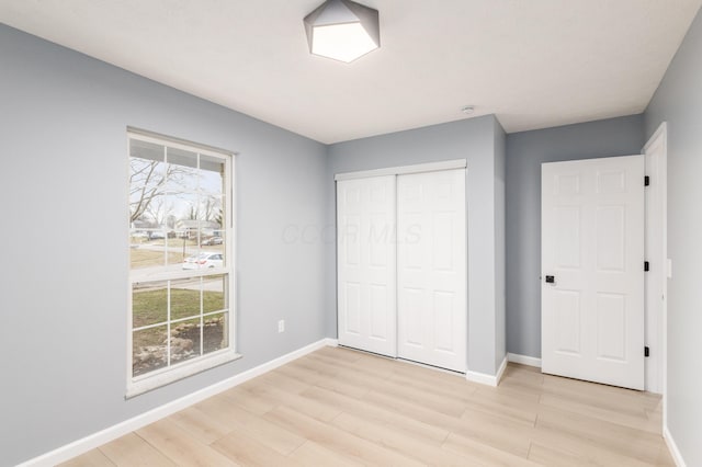 unfurnished bedroom with light wood finished floors, baseboards, and a closet