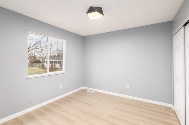 unfurnished bedroom featuring light wood finished floors, visible vents, baseboards, and a closet