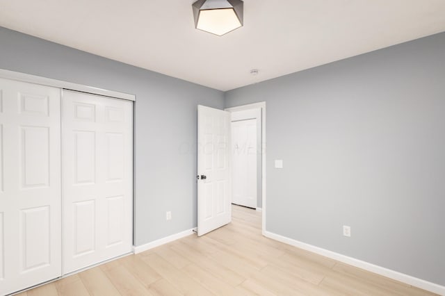 unfurnished bedroom featuring a closet, light wood-style flooring, and baseboards