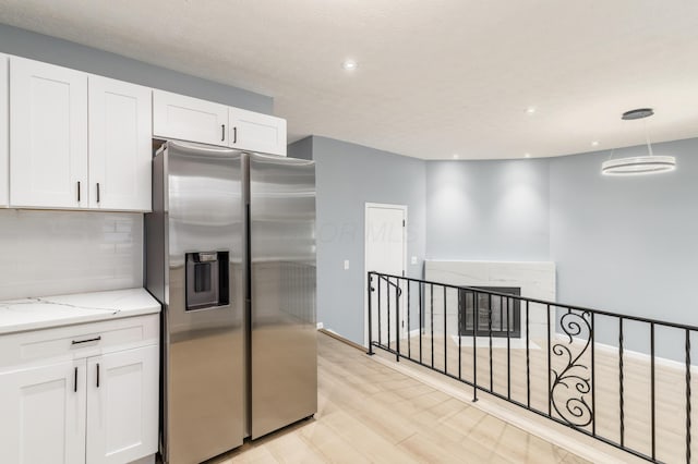 kitchen featuring tasteful backsplash, white cabinetry, stainless steel refrigerator with ice dispenser, and light stone counters