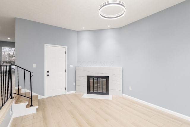 unfurnished living room with a fireplace, recessed lighting, stairway, wood finished floors, and baseboards