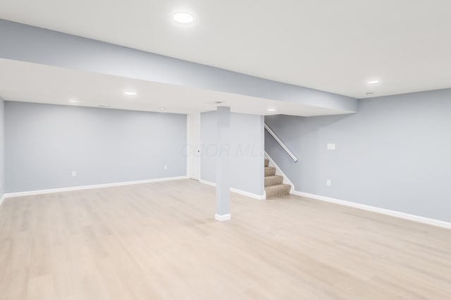 finished below grade area with stairs, light wood finished floors, recessed lighting, and baseboards