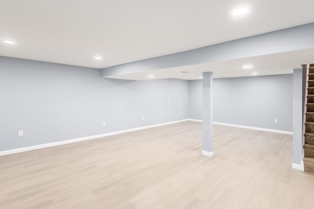 finished basement with light wood-style floors, recessed lighting, stairway, and baseboards