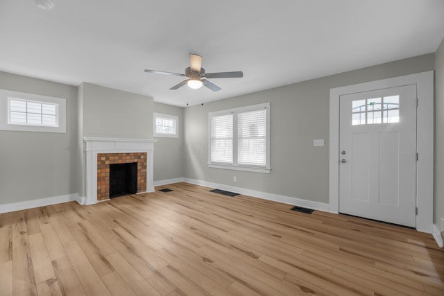 unfurnished living room featuring baseboards, visible vents, a fireplace, and light wood finished floors