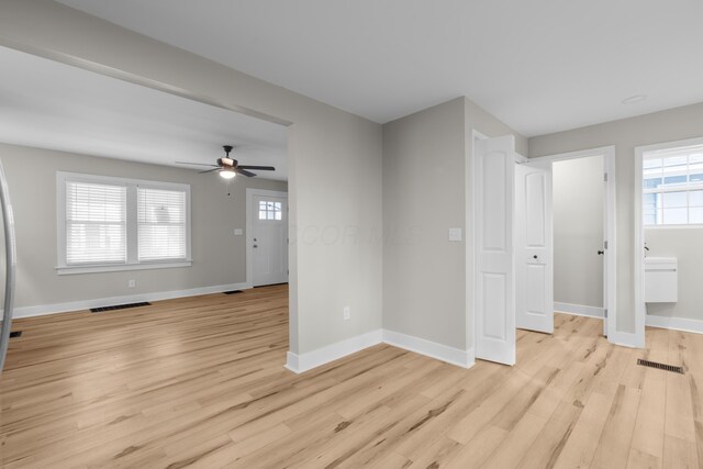 unfurnished living room featuring visible vents, plenty of natural light, and light wood-style flooring