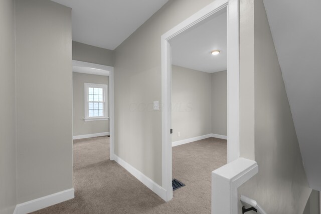 hall with carpet floors, visible vents, and baseboards