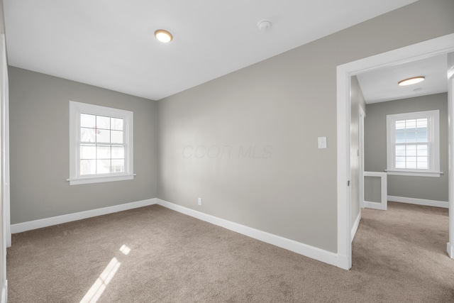 carpeted empty room with plenty of natural light and baseboards