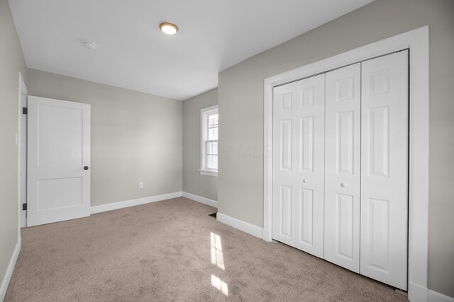 unfurnished bedroom with carpet, baseboards, and a closet