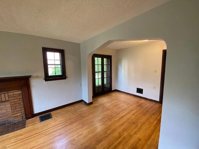 spare room with visible vents, arched walkways, a healthy amount of sunlight, and light wood-style flooring