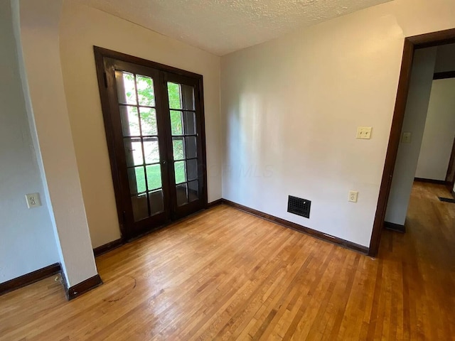 entryway featuring light wood-type flooring, baseboards, a textured ceiling, and french doors