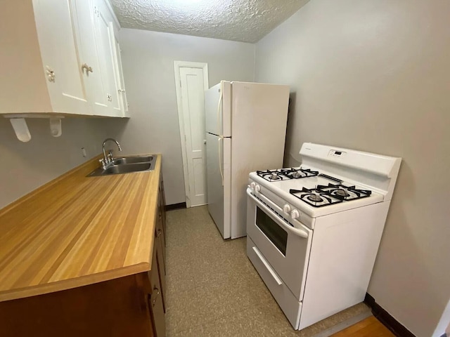 kitchen with light floors, white cabinets, white appliances, a textured ceiling, and a sink