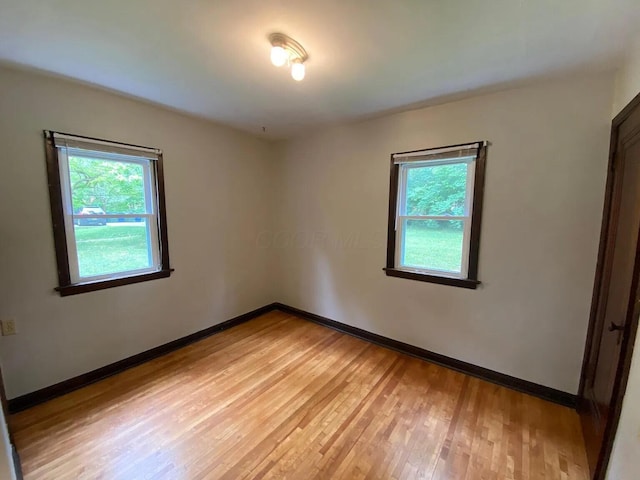 spare room with plenty of natural light, baseboards, and light wood finished floors