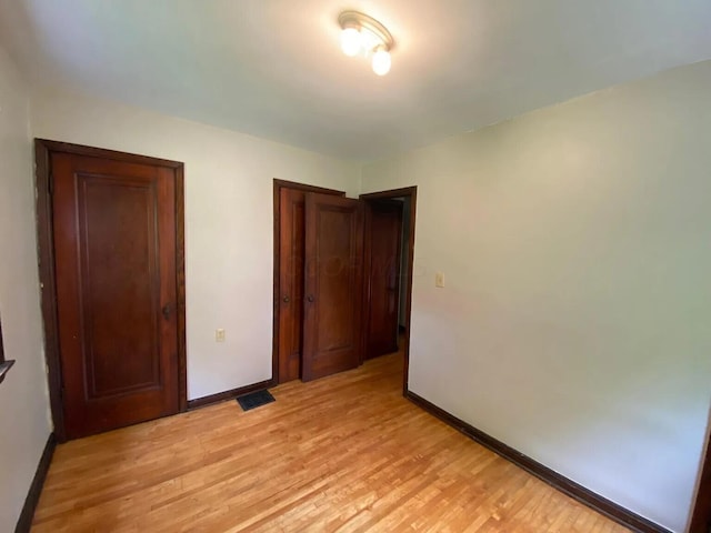 unfurnished bedroom with visible vents, baseboards, a closet, and light wood-style flooring