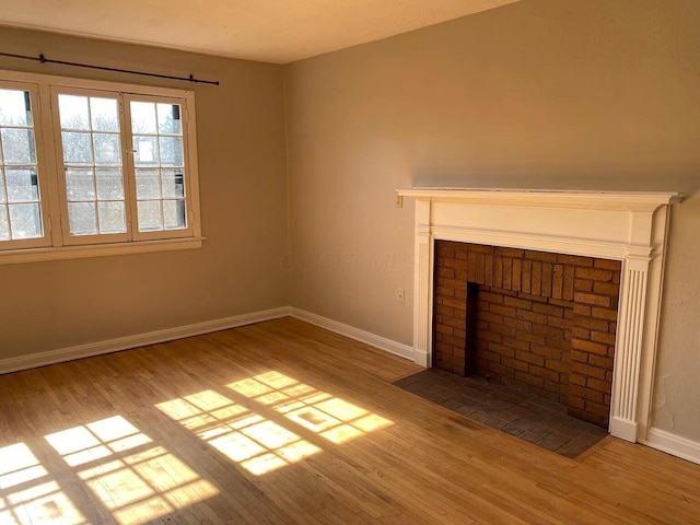 unfurnished living room featuring baseboards, wood finished floors, and a fireplace