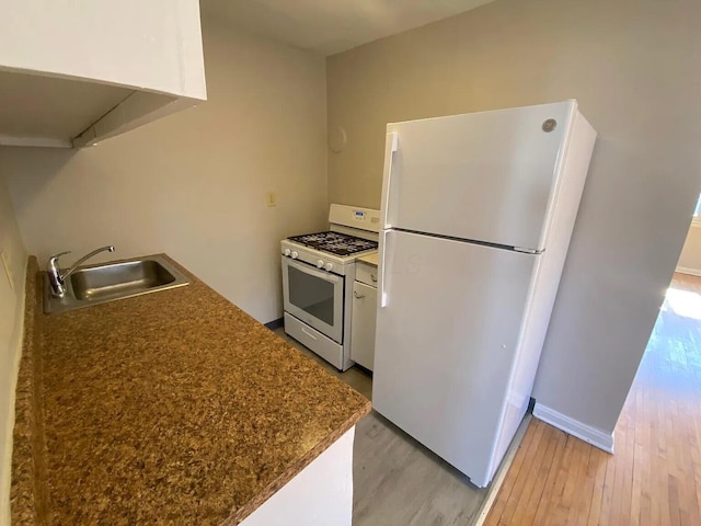 kitchen with white appliances, baseboards, light wood-style flooring, a sink, and dark countertops