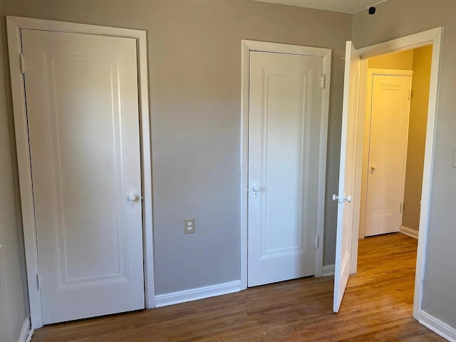 unfurnished bedroom featuring wood finished floors and baseboards