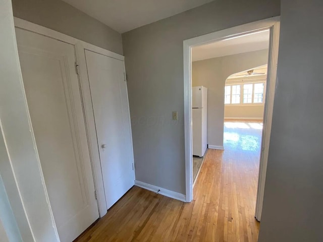 corridor featuring light wood-style flooring and baseboards