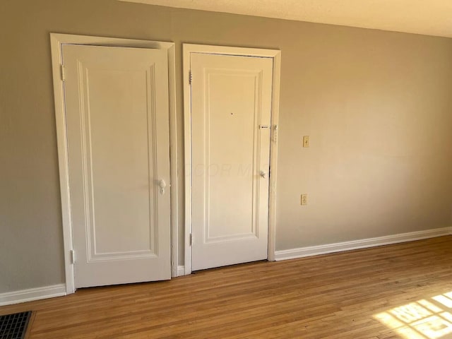 unfurnished bedroom featuring visible vents, baseboards, and light wood-style floors