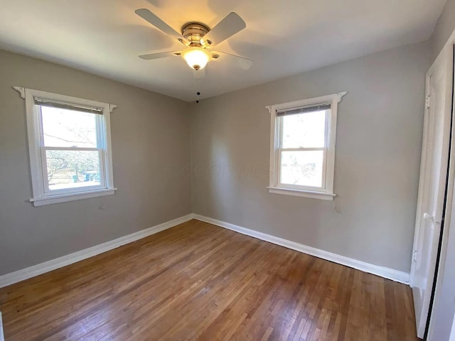 empty room featuring a healthy amount of sunlight, baseboards, and wood finished floors