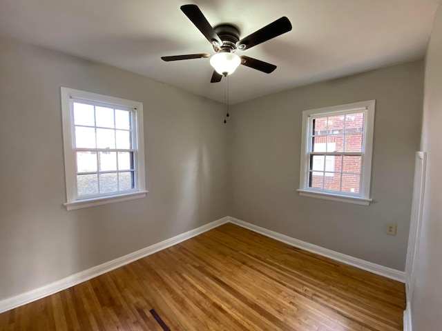 empty room featuring a wealth of natural light, baseboards, and wood finished floors