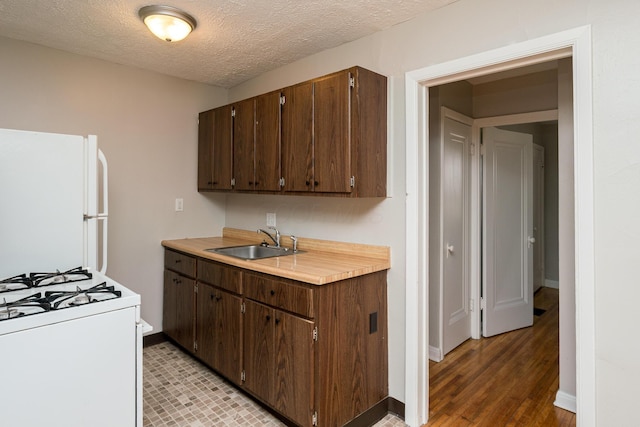 kitchen featuring white appliances, dark brown cabinets, light countertops, and a sink