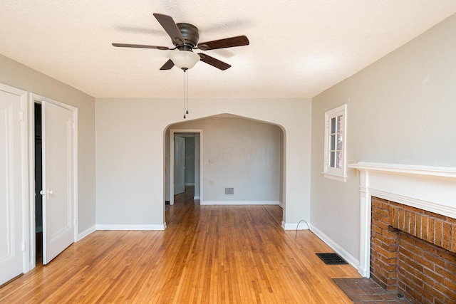 spare room with visible vents, arched walkways, baseboards, and light wood-style flooring