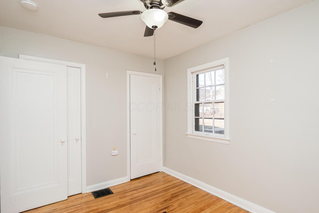 unfurnished bedroom with visible vents, light wood-style flooring, a ceiling fan, and baseboards