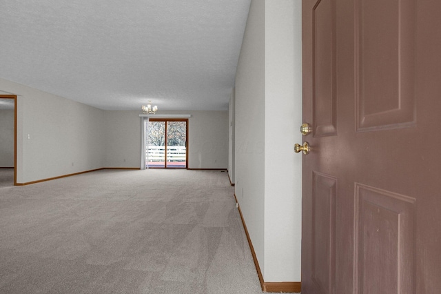 empty room with an inviting chandelier, baseboards, carpet floors, and a textured ceiling