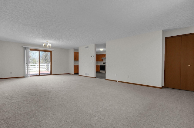 unfurnished living room with a chandelier, light colored carpet, a textured ceiling, and baseboards