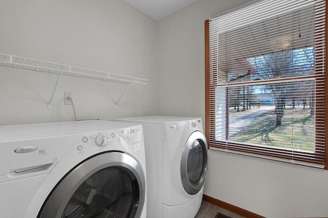 clothes washing area featuring baseboards, laundry area, and washer and clothes dryer