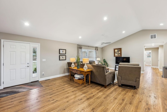 living area with lofted ceiling, visible vents, a ceiling fan, light wood-type flooring, and baseboards