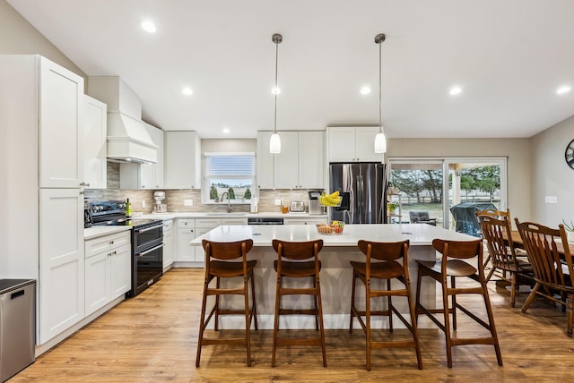 kitchen featuring a kitchen island, light countertops, double oven range, stainless steel fridge with ice dispenser, and custom range hood