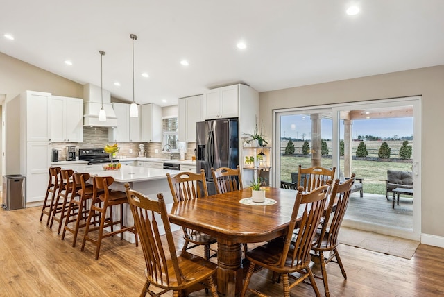 dining space with vaulted ceiling, baseboards, light wood-style flooring, and recessed lighting