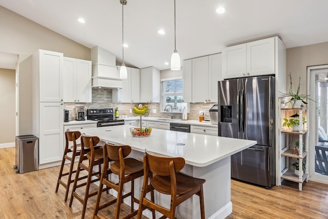 kitchen with custom exhaust hood, stainless steel appliances, lofted ceiling, light countertops, and a sink