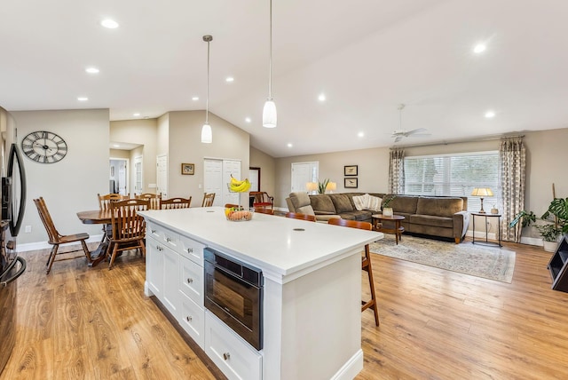 kitchen with light wood-type flooring, white cabinetry, black microwave, and a center island