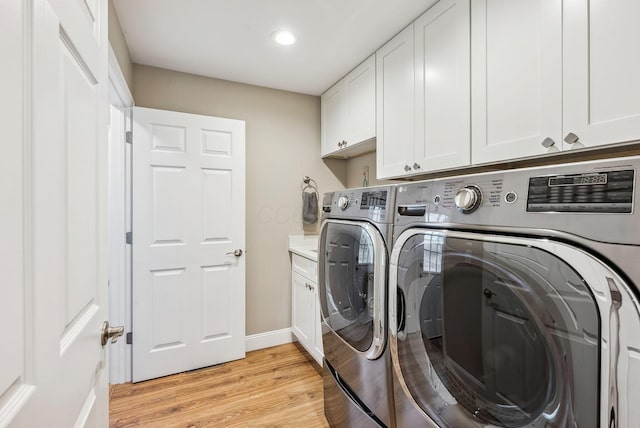 washroom with baseboards, washing machine and clothes dryer, cabinet space, and light wood-style floors