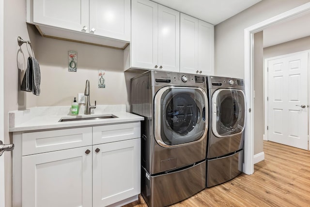 laundry room with cabinet space, a sink, separate washer and dryer, light wood-type flooring, and baseboards