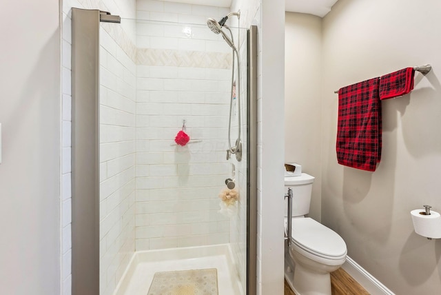 full bath featuring toilet, a stall shower, and baseboards