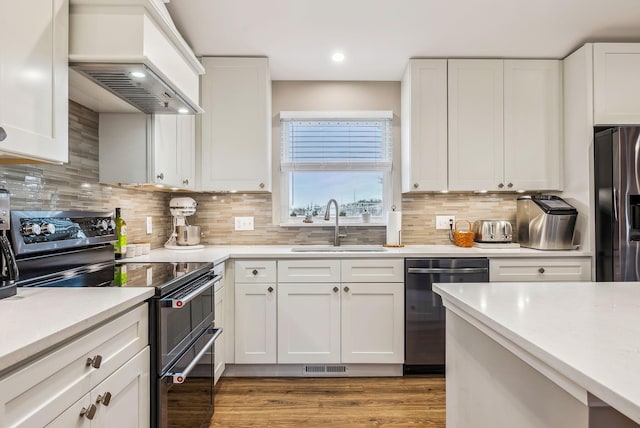 kitchen with stainless steel appliances, light countertops, visible vents, a sink, and premium range hood