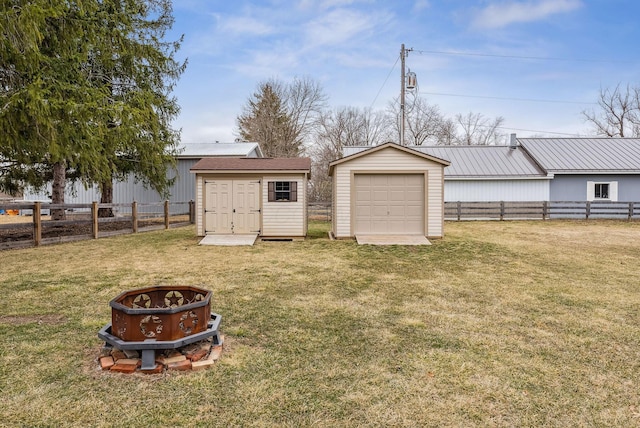 view of yard featuring a fenced backyard, an outdoor structure, a fire pit, and a shed