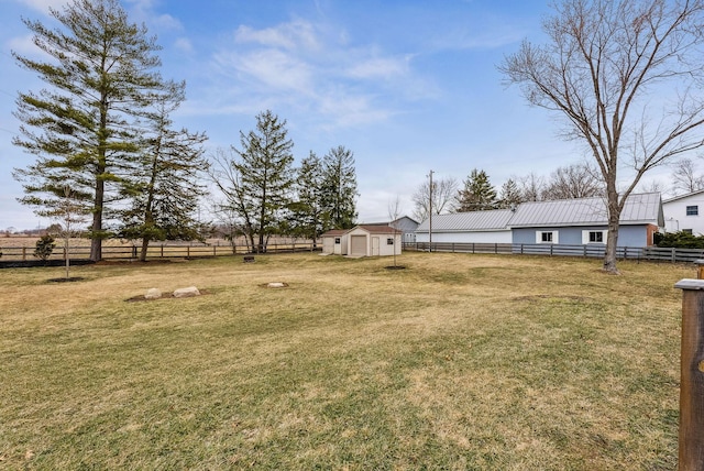 view of yard featuring a storage unit, an outdoor structure, fence, and a detached garage