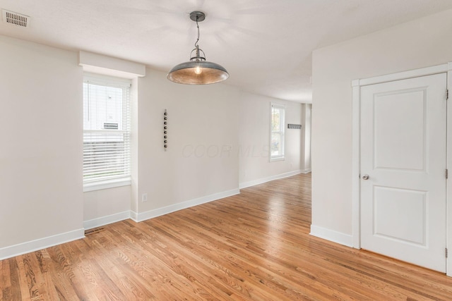 unfurnished room featuring visible vents, light wood-style flooring, and baseboards