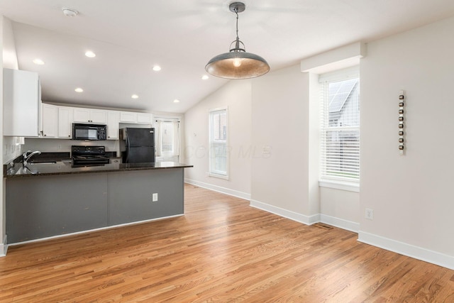 kitchen featuring a peninsula, a sink, light wood-style floors, white cabinets, and black appliances