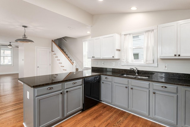 kitchen with light wood finished floors, dishwasher, a peninsula, gray cabinetry, and a sink