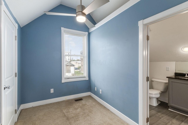 bedroom featuring connected bathroom, carpet floors, visible vents, baseboards, and vaulted ceiling