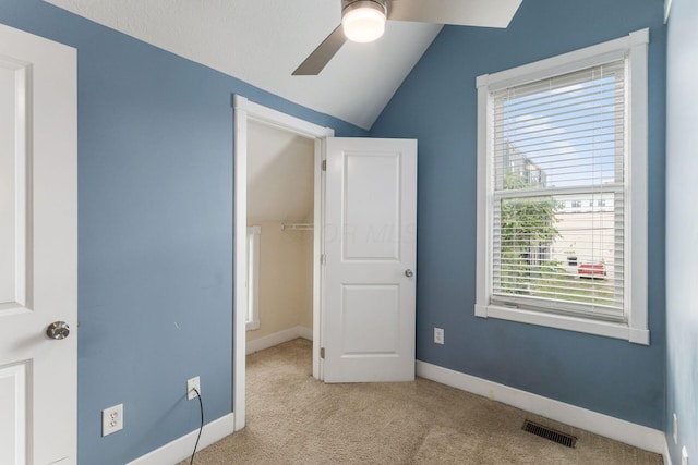 unfurnished bedroom featuring baseboards, visible vents, a ceiling fan, vaulted ceiling, and carpet floors