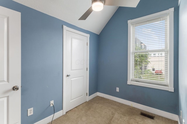 unfurnished bedroom featuring lofted ceiling, a ceiling fan, visible vents, baseboards, and carpet