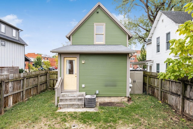 rear view of property featuring a yard, central air condition unit, a shingled roof, entry steps, and a fenced backyard