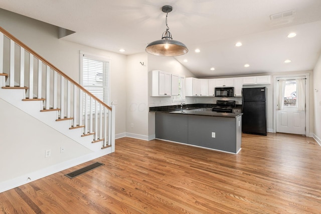 kitchen featuring dark countertops, white cabinetry, a peninsula, and black appliances