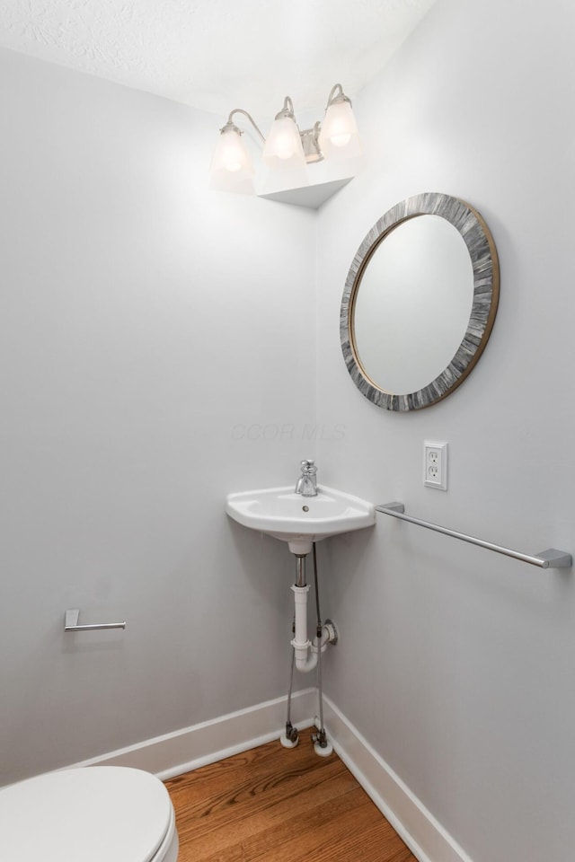 bathroom featuring wood finished floors, toilet, and baseboards